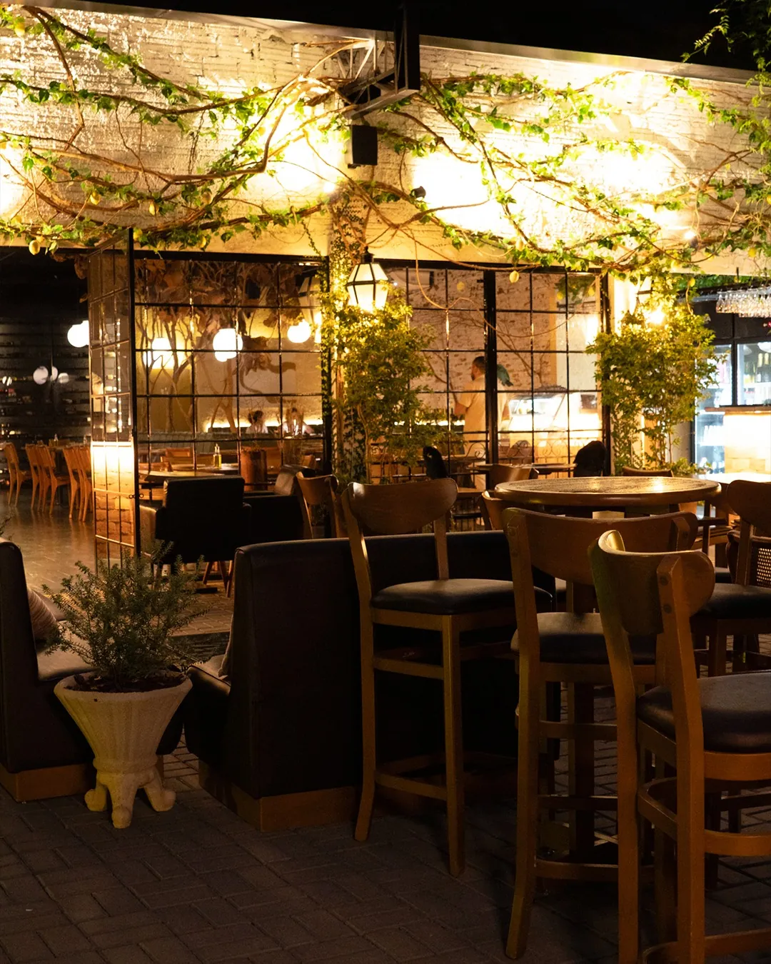Pérgola com vinhas e luzes baixas sobre a área externa da cantina